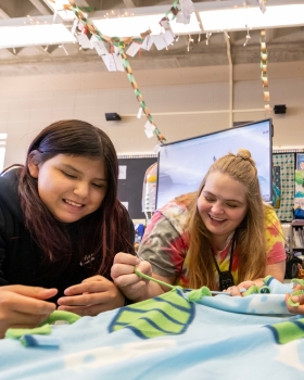 Photograph of educator and student smiling while engaging in an activity together.